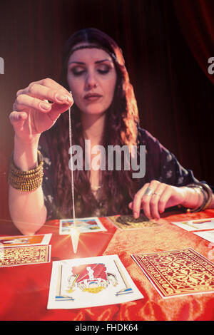 Immagine composita femminile di fortune teller usando pendolo Foto Stock