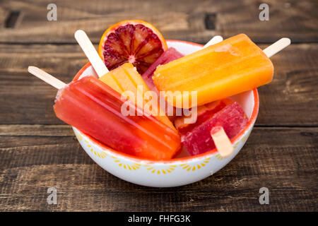 Ciotola di diverso colore arancione in casa ghiaccioli e sangue fetta di arancia Foto Stock
