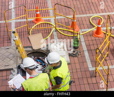 Gli ingegneri di telefono (maschio e femmina) installazione di cavi a fibre ottiche. Foto Stock