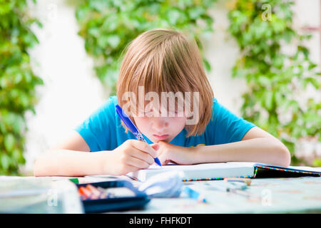 Ragazzo con capelli biondi Studiare all'aperto Foto Stock