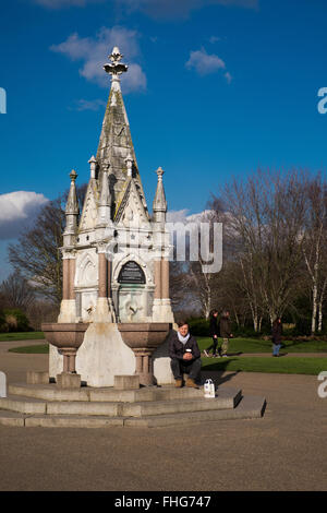 Tourist si appoggia per la fontanella in Regents Park in inverno London Inghilterra England Foto Stock