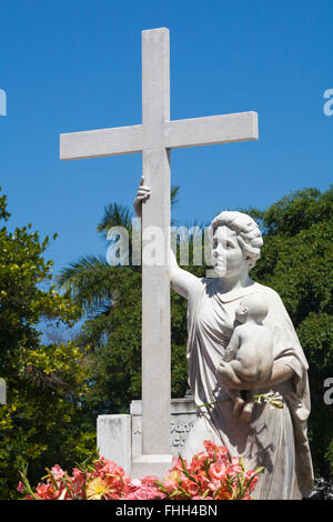 Statua scultura di donna tenendo il bambino e la croce sulla tomba al cimitero di Colon, Havana, Cuba, West Indies, dei Caraibi e America centrale Foto Stock