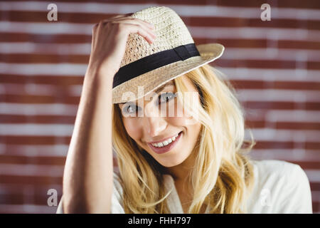 Bella donna bionda tenendo il suo cappello Foto Stock