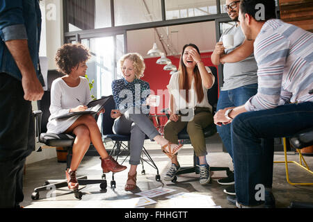 Inquadratura di un gruppo di giovani professionisti di aziende aventi una riunione. Diversi gruppi di giovani designer sorridente durante una riunione a t Foto Stock