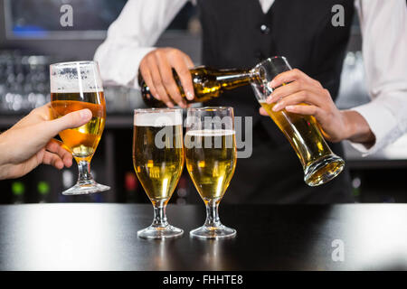 Il barista che serve birra al bancone bar Foto Stock