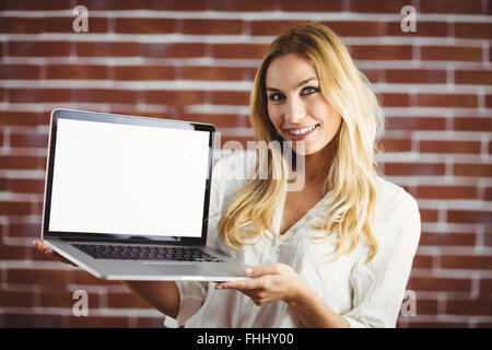 Bella donna bionda che mostra il suo computer portatile Foto Stock