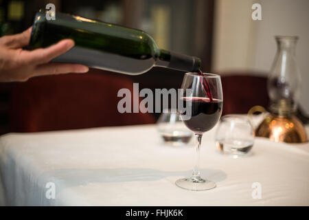 Cameriere versando un bicchiere di vino rosso Foto Stock