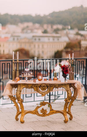 Lussuoso hotel splendido tavolo in stile orientale decorato con fiori e candele. Torta di Nozze e spuntini Foto Stock