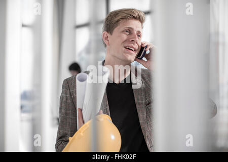 Uomo con elmetto parlando al telefono Foto Stock