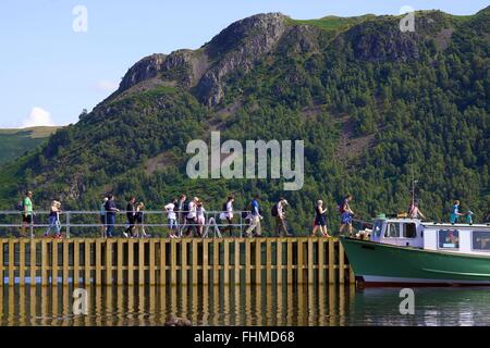 Parco Nazionale del Distretto dei Laghi. I turisti di salire a bordo di un lancio da un pontile sul lago Ullswater. Foto Stock