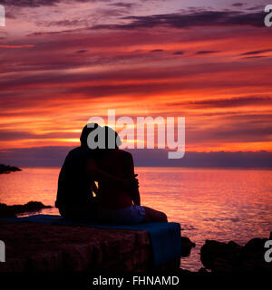 Silhouette di coppia romantica a guardare il tramonto sul mare Foto Stock