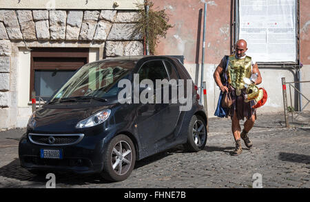 Un gladiatore romano street performer capi al lavoro dopo aver indossato il suo costume vicino al Colosseo. Foto Stock