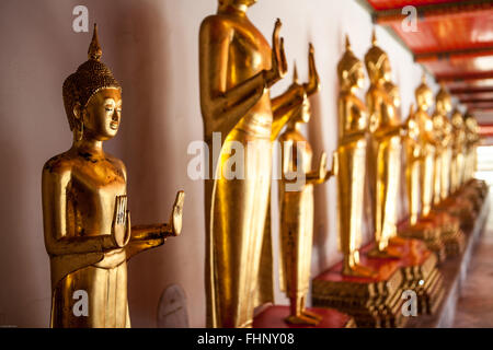 Una fila di golden buddha permanente al Wat Pho, un famoso tempio e di attrazione turistica a Bangkok, in Thailandia Foto Stock