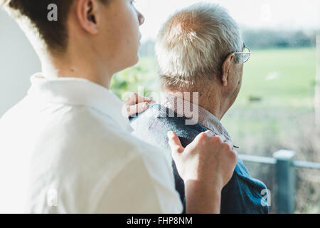 Vista posteriore del senior l uomo e la sua infermiera geriatrica Foto Stock