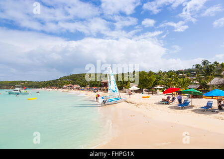 Vista panoramica di Dickenson Bay, a nord Antigua, con ombrelloni e sedie a sdraio e sandali barche a vela sulla spiaggia Foto Stock