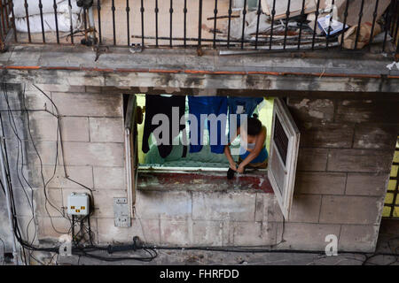 L'Avana, Cuba - 27 Gennaio 2016: la donna che si estendono i vestiti alla finestra della sua casa nel quartiere di Habana vieja Foto Stock