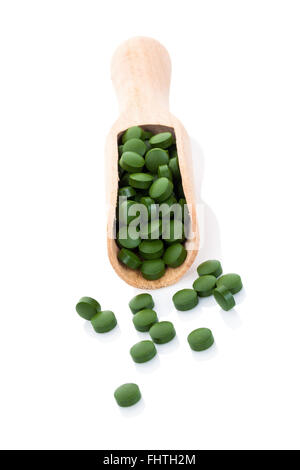 Pillole di verde sul cucchiaio di legno isolata. Foto Stock