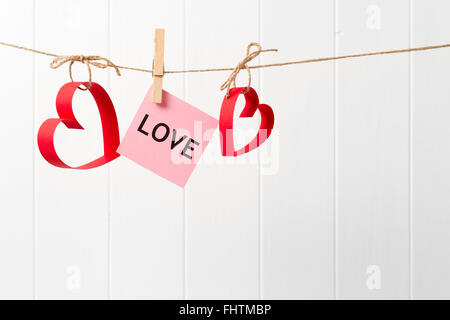 Due carta rossa cuori con amore cantare appeso sul concetto di corda per le vacanze il giorno di San Valentino Foto Stock