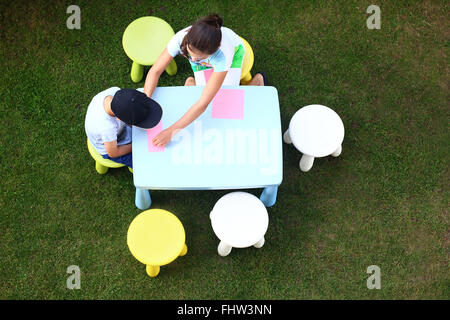 Divertenti attività all'aperto. Divertimento creativo per la noia. I bambini giocano in giardino si disegna con matite colorate Foto Stock