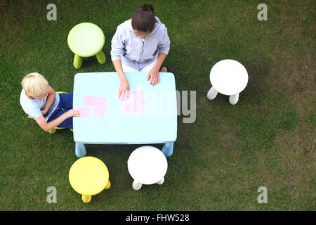 Divertenti attività all'aperto. Divertimento creativo per la noia. I bambini giocano in giardino si disegna con matite colorate Foto Stock