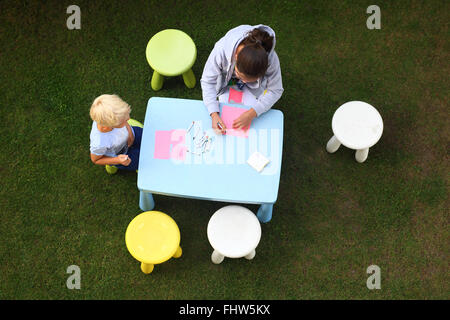 Divertenti attività all'aperto. Divertimento creativo per la noia. I bambini giocano in giardino si disegna con matite colorate Foto Stock