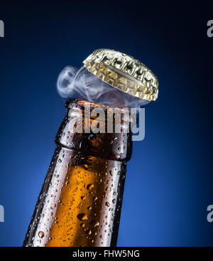 Apertura del tappo di birra con il gas in uscita. Foto Stock