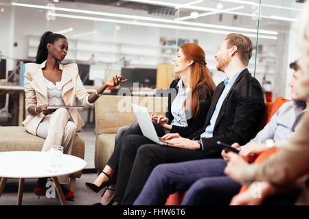 La gente di affari la conversazione con la tecnologia a portata di mano. Scambio di idee nuove e di brainstorming tra colleghi Foto Stock