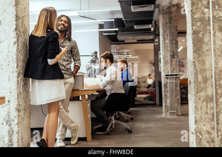 Colleghi di lavoro parlando in ufficio e sorridente Foto Stock