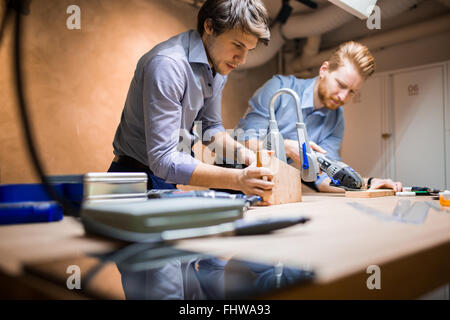 Due designer che lavorano insieme in officina con utensili di precisione Foto Stock