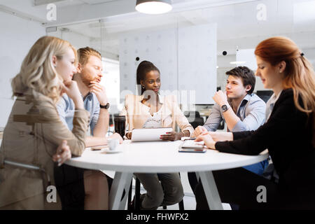 Un gruppo di persone di affari seduti alla scrivania e discutere di nuove idee Foto Stock