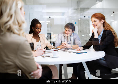 Un gruppo di persone di affari seduti alla scrivania e discutere di nuove idee Foto Stock