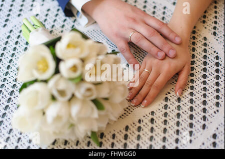 Il palmo della mano tocca lo sposo sposa. Le mani sul pizzo tovaglie in cafe. Bouquet sfocata. Luce naturale dalla win Foto Stock
