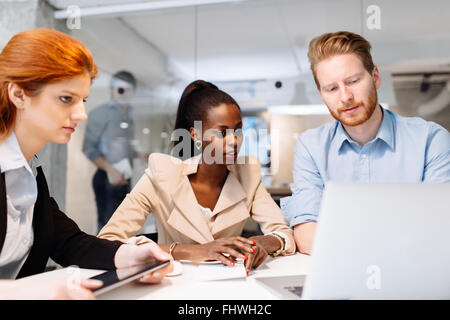 Un gruppo di persone di affari seduti alla scrivania e avente una riunione sulla strategia futura Foto Stock