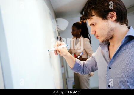 Smart People scrivere sulla lavagna nella ricerca di una soluzione Foto Stock