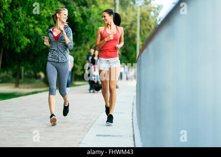 Due donne sportivi jogging in città mentre si ascolta la musica Foto Stock