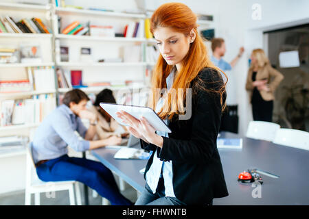 Imprenditrice in ufficio moderno lavora con tavoletta in mano Foto Stock