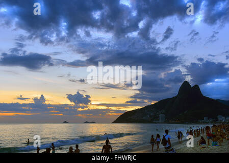 I bagnanti della spiaggia di Ipanema al tramonto Foto Stock