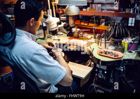 Gioielliere lavorando su metalli con dispositivo ottico che consente per lavori di precisione Foto Stock