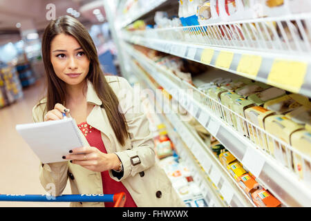 Bella donna shopping nel supermercato e decidere cosa acquistare Foto Stock