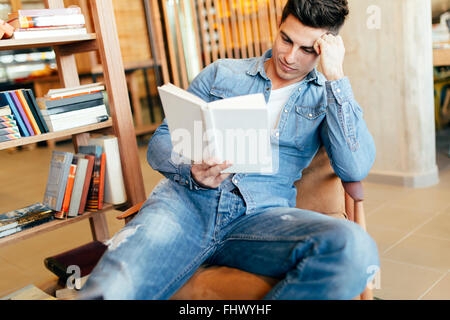 Uomo bello studio mediante la lettura di libri e di preparazione per l'esame Foto Stock
