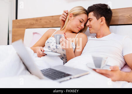 Matura in amore tenendo le tazze di caffè e sorridente Foto Stock