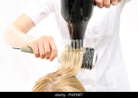 Pettinare i capelli a spazzola di essiccazione. La donna presso il parrucchiere, barbiere modelli capelli su una spazzola circolare. Parrucchiere capelli secchi Foto Stock