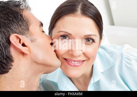Uomo anziano baciando la sua donna sorridente sulla guancia Foto Stock