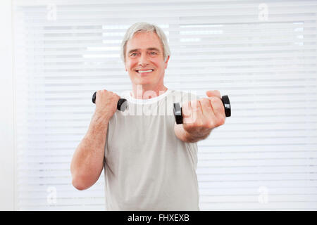 Senior uomo facendo un allenamento fitness con manubri in palestra Foto Stock