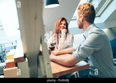 Bella coppia innamorata di bere il vino in casa e a parlare in modo casuale Foto Stock