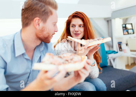 Giovane condividere pizza e mangiare insieme felicemente Foto Stock