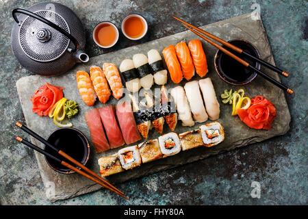 Set di sushi nigiri sushi e panini con tè serviti su pietra grigio ardesia su sfondo di metallo Foto Stock