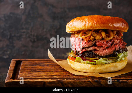 Pastrami Burger con fette di arrosto di manzo e cipolle fritte anelli su sfondo nero Foto Stock