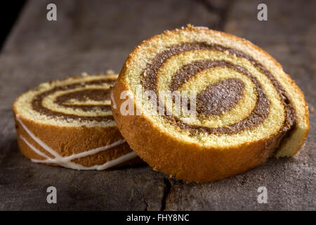 Fette di pan di spagna rotolo su sfondo di legno Foto Stock