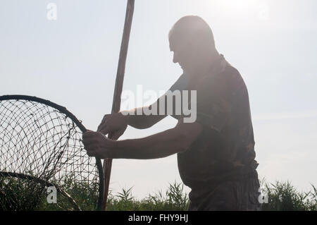 Pescatore nel fiume al lavoro, Delta Dunarii in Romania Foto Stock